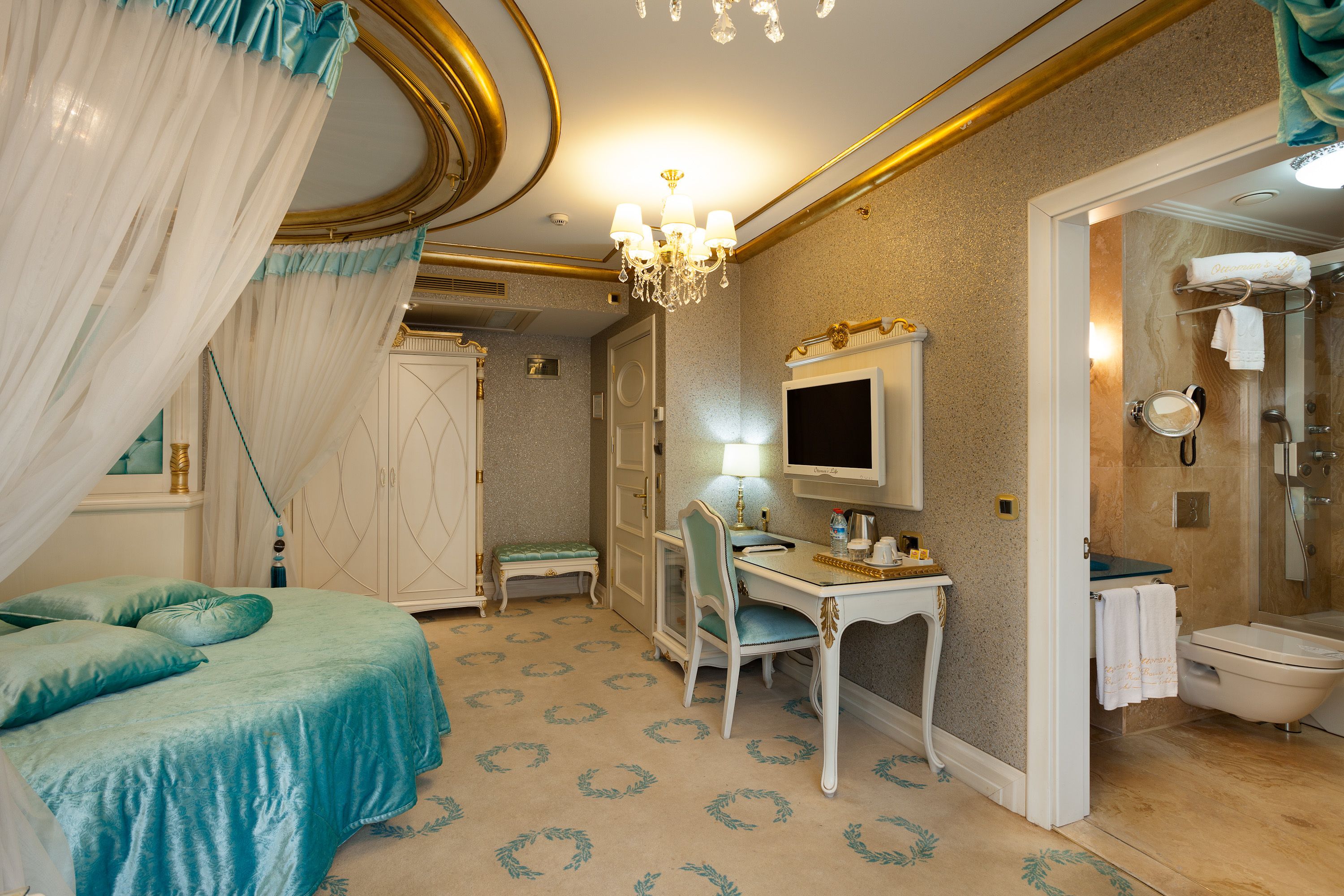 A bedroom with a bed, a desk, and a vanity with a mirror.