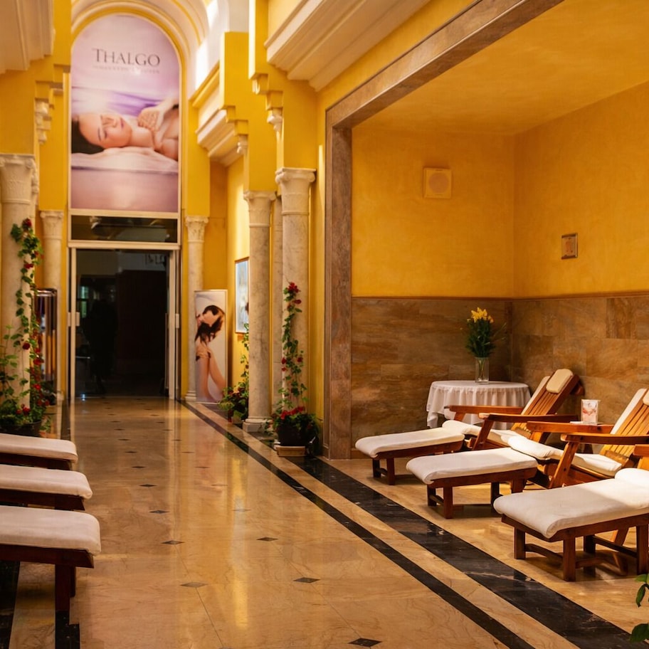 A spa area with wooden loungers, a reception desk, and a poster advertising Thalgo.
