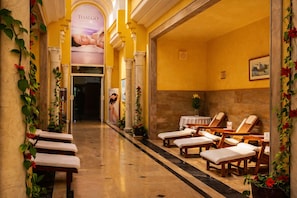 A spa area with wooden loungers, a reception desk, and a poster advertising Thalgo.
