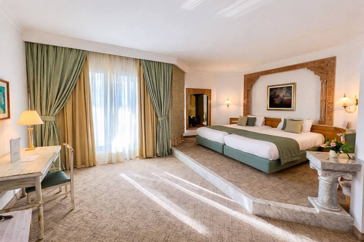 Een hotelkamer met een groot bed, een bureau, een stoel en een bureaulamp.