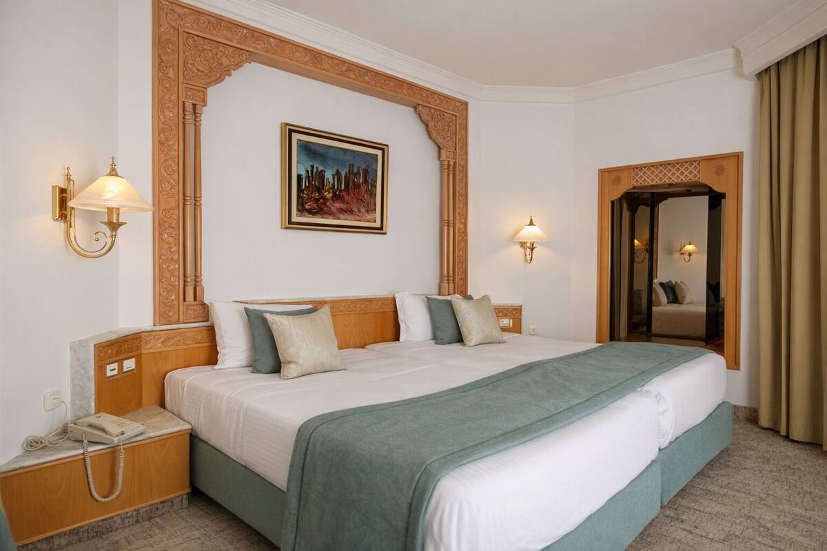 Een hotelkamer met een groot bed, een schilderij aan de muur en een spiegel.