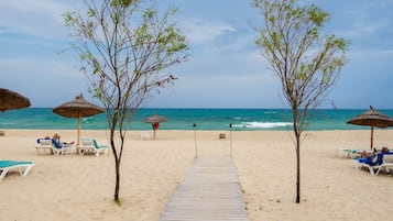 En la playa, sillas reclinables de playa, sombrillas, toallas de playa