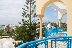 Un balcón con barandillas azules que da a una zona turística con palmeras y vistas al mar.