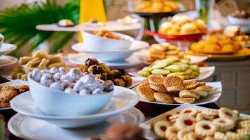 A buffet with various food items including cookies, pastries, and a bowl of chocolate-covered treats.