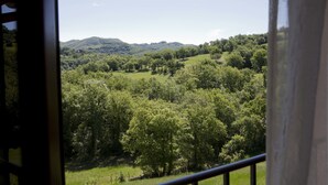 A view from a window overlooking a lush green landscape with rolling hills and dense trees. - Relais Parco del Subasio (Assisi)