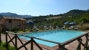 A rectangular pool with a wooden deck and a fence. - Relais Parco del Subasio (Assisi)