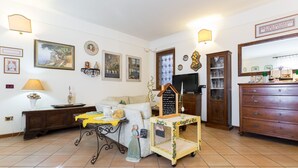 Una sala de estar con un sofá, una mesita con una lámpara, un estante decorativo y un aparador de madera.