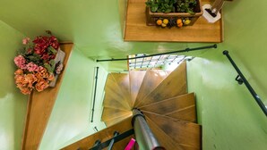 Una escalera de caracol con detalles de madera, barandilla y un pequeño estante con plantas y frutas.