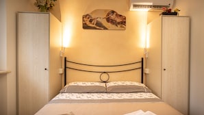 A neatly made bed with floral bedding, a wall-mounted artwork, and two bedside lamps.