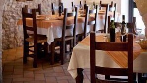 A stone archway leading to a dining area with tables and chairs, and a rustic stone wall. - Il Castello (Assisi)