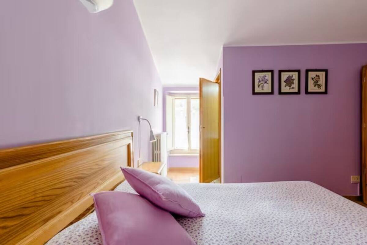 A bedroom with a wooden headboard, a bed with a patterned bedspread, and three framed pictures on the wall.