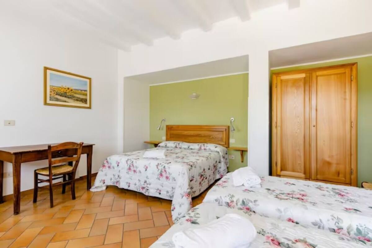 A bedroom with two beds, a wooden desk, a chair, and a wardrobe.