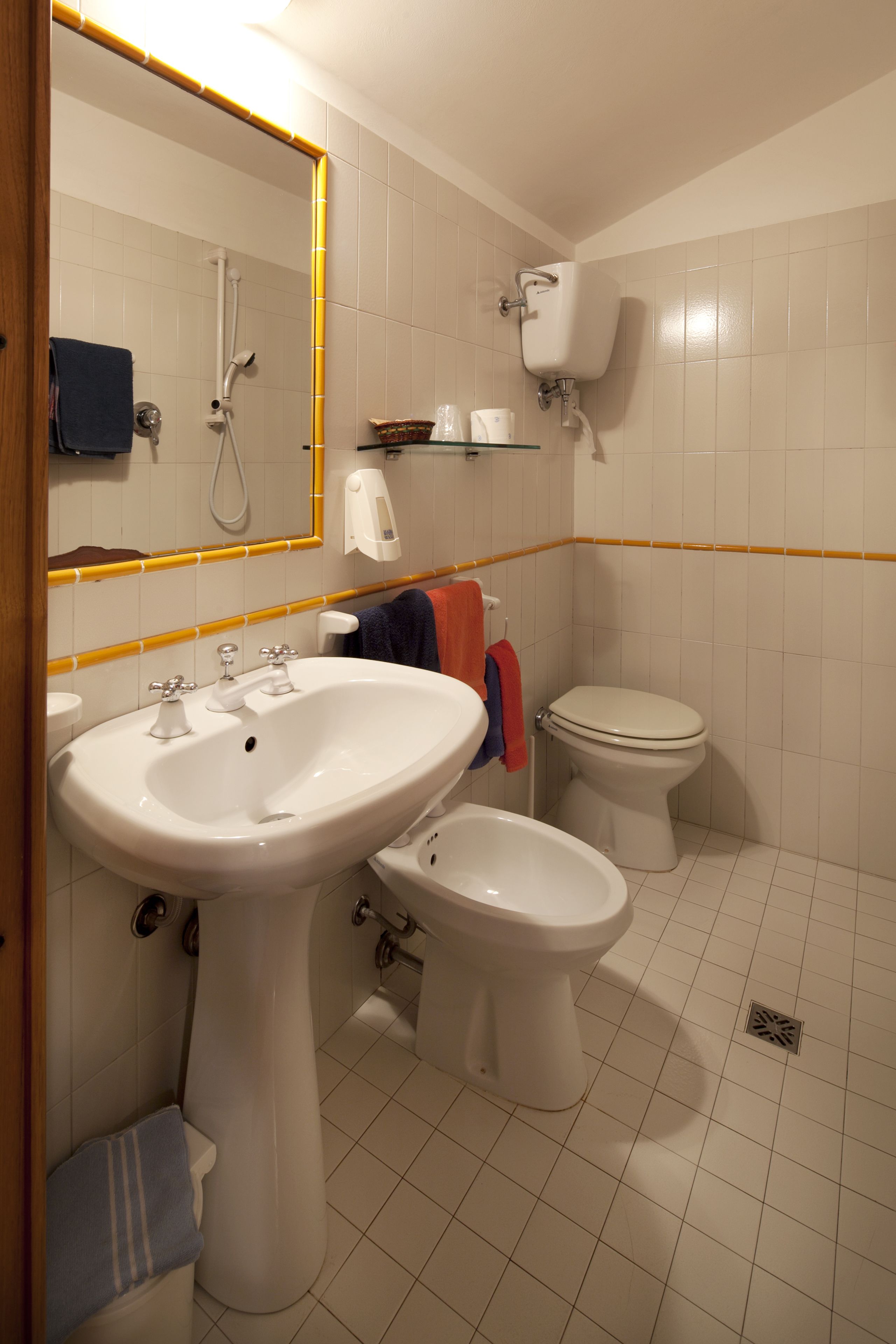 Un baño con lavabo, inodoro, bidé y espejo con marco amarillo.