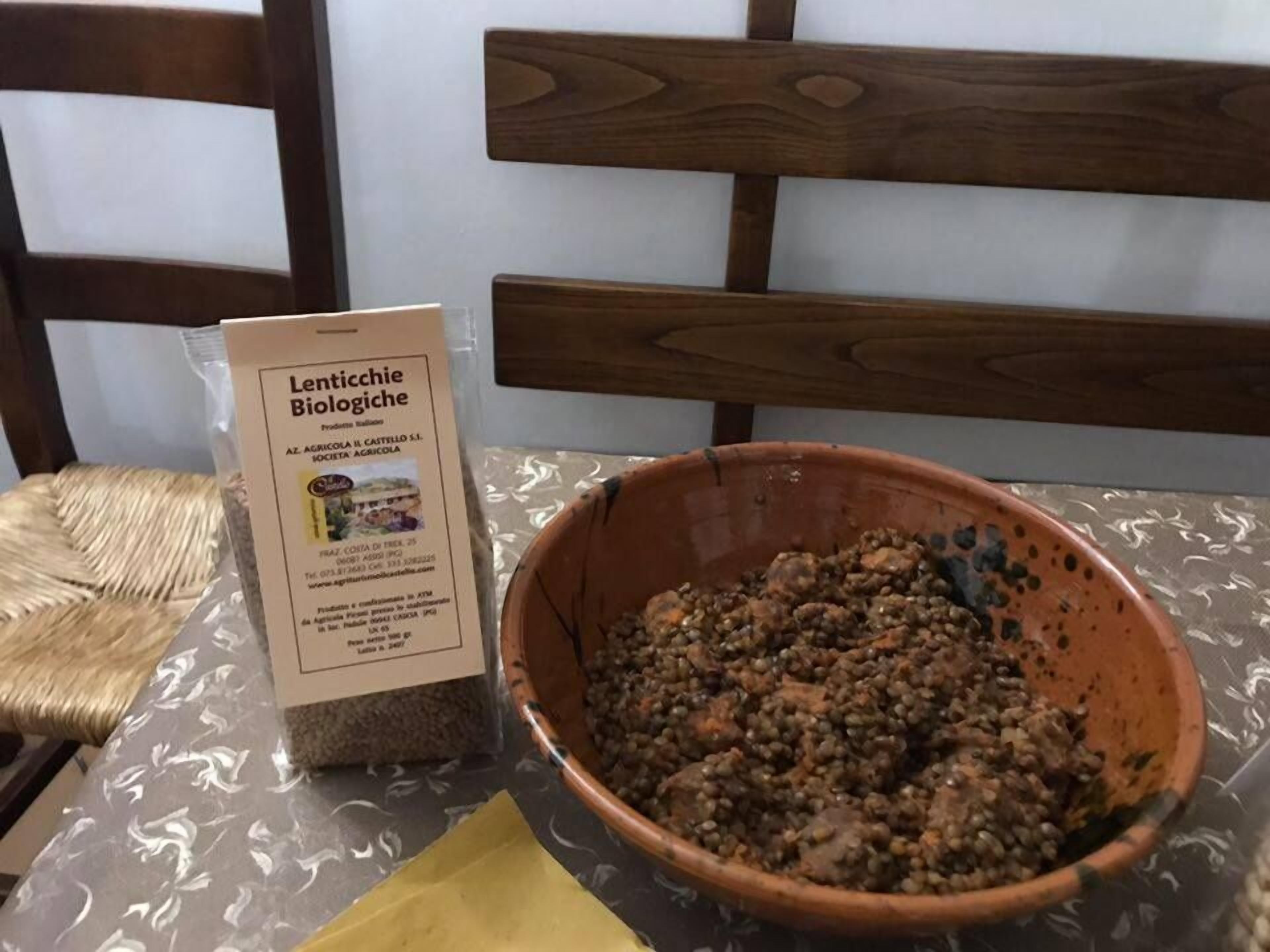 Une table avec une pancarte indiquant « Lenticchie Biologiche » et un bol de lentilles.