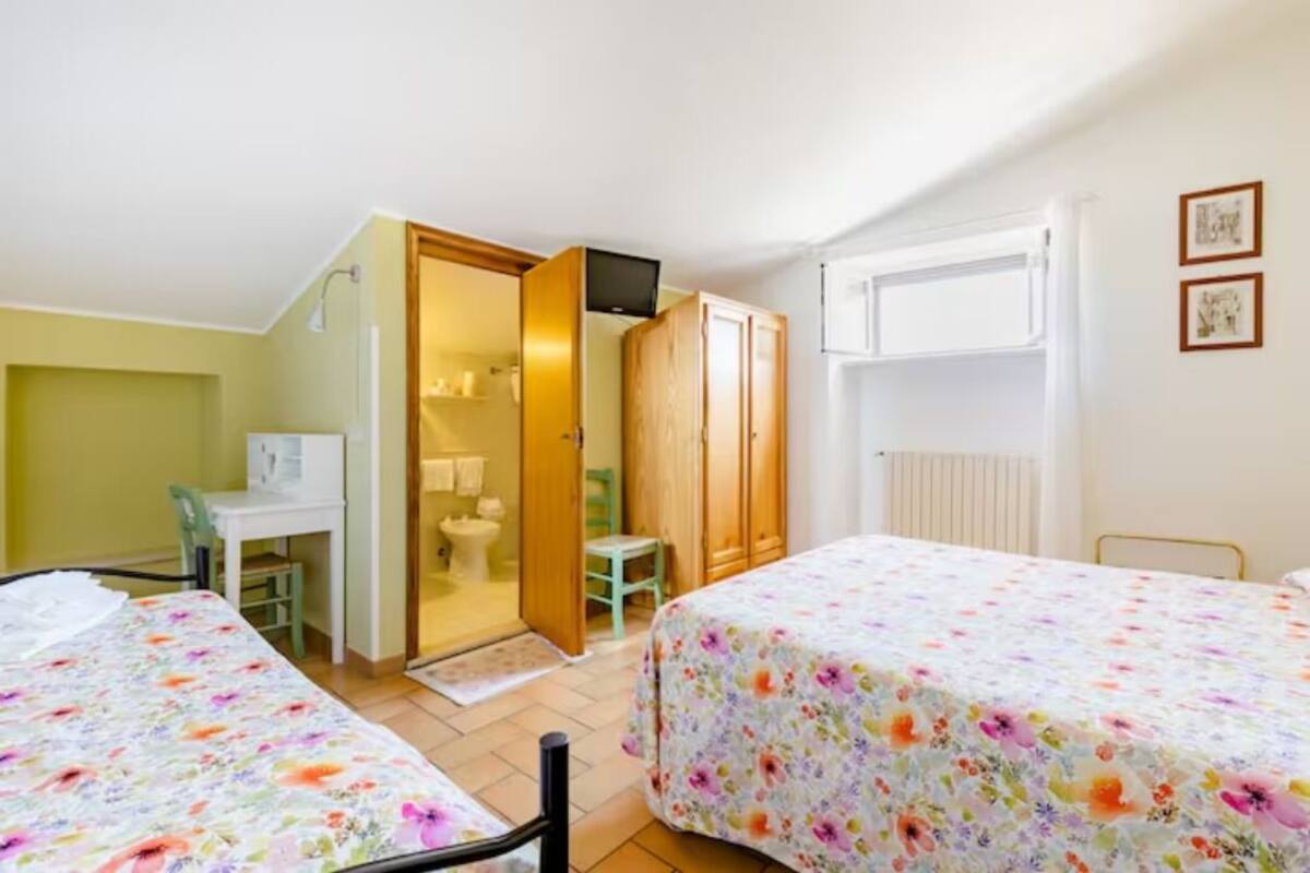 A bedroom with two beds, a desk, a chair, and a wardrobe.