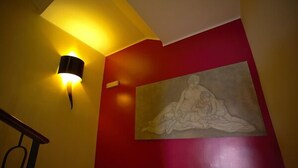 A staircase with a wall-mounted light fixture and a large painting.