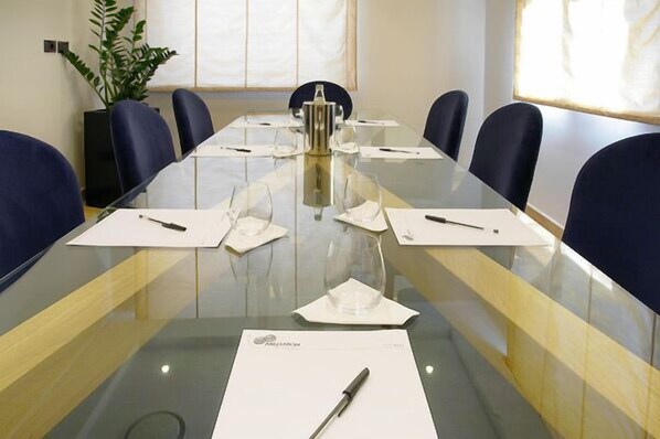 A conference room with a glass table, six chairs, and a plant.