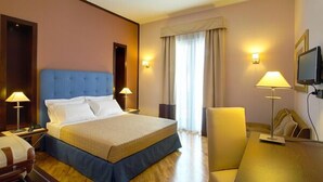 A hotel room with a large bed, bedside lamps, a desk, and a television.