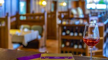Angolo bar con un bicchiere di vino rosso, un menu e una cantina sullo sfondo.