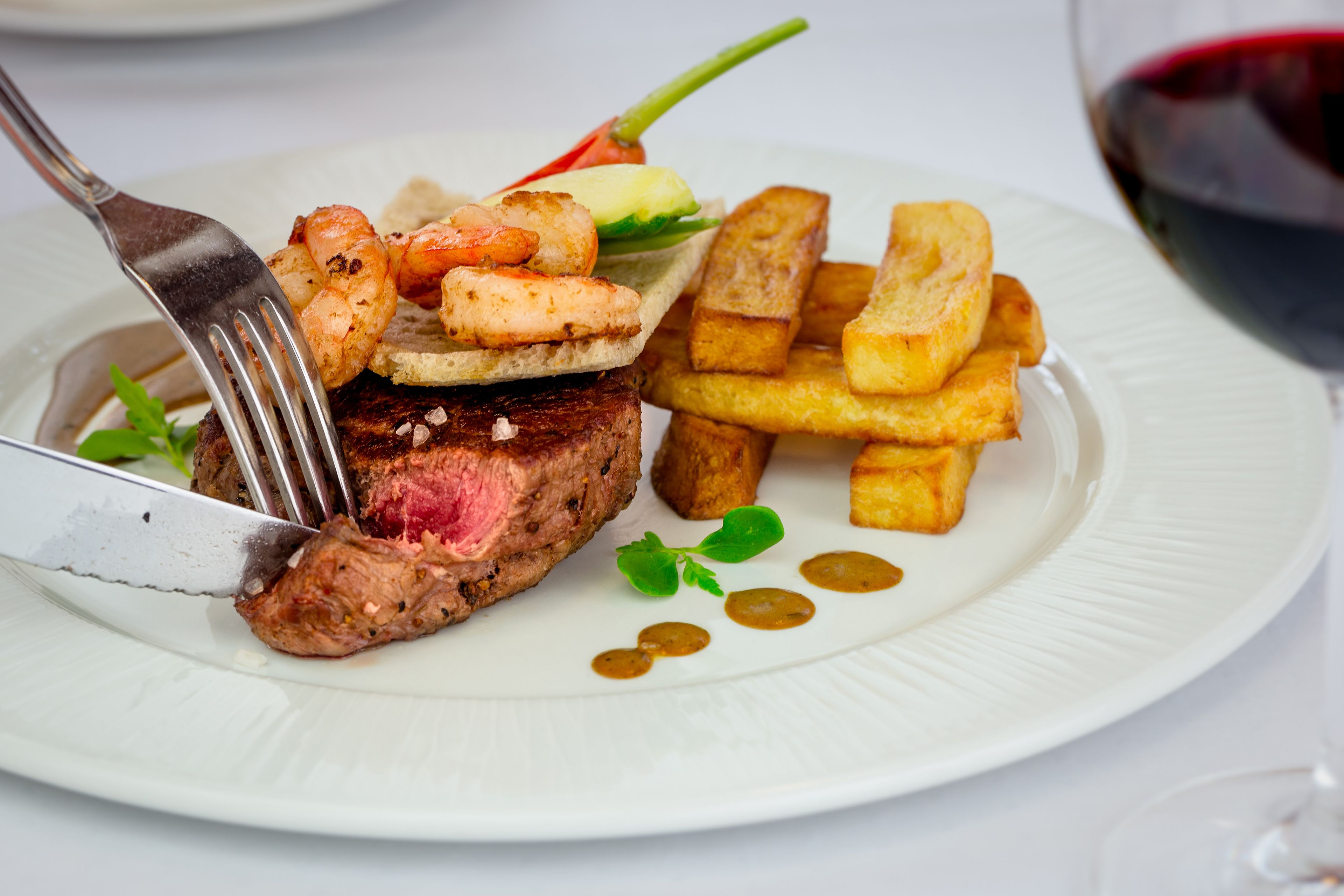 Un plato con bistec, camarones y papas fritas.