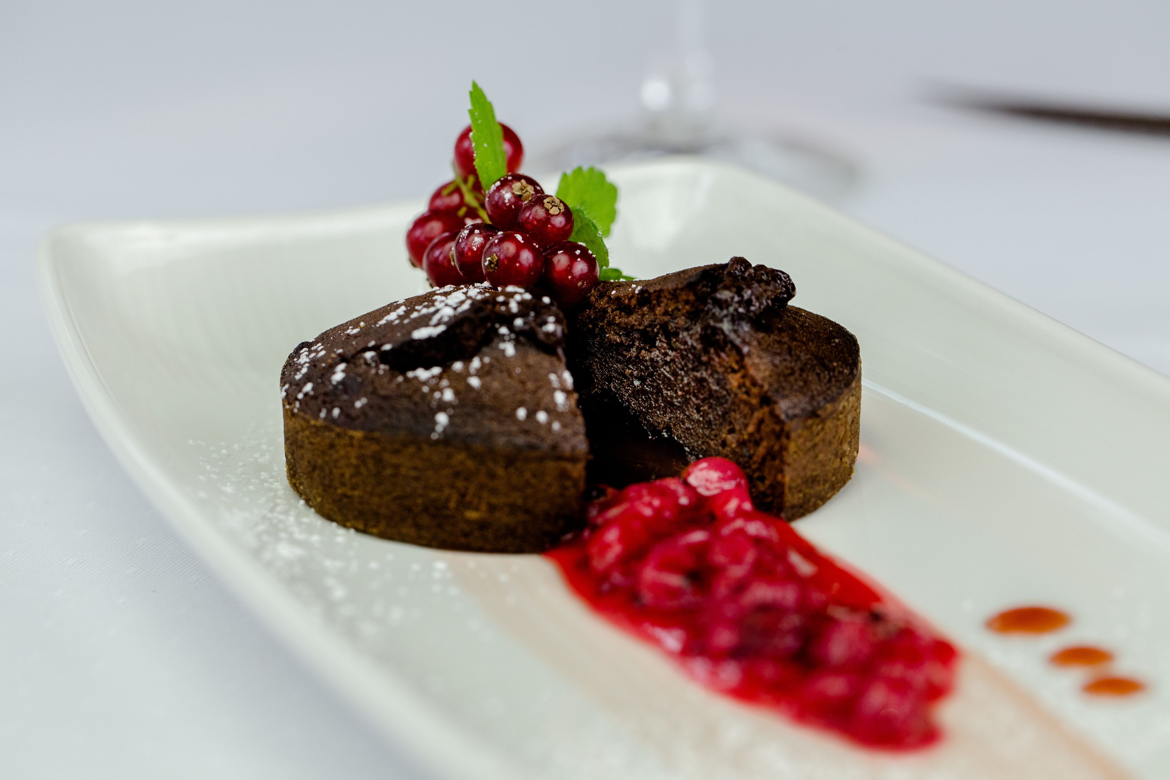 Un plato de postre con pastel de chocolate, bayas y una copa de vino.