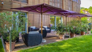 Un patio con mobiliario exterior, plantas en macetas y un edificio con el nombre "Betekins" a la vista.