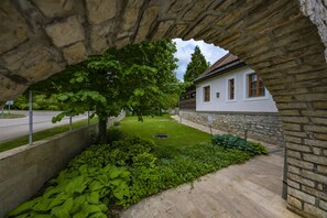 A stone archway leading to a white house with a garden. - Betekints Wellness és Konferencia Hotel (Veszprem)