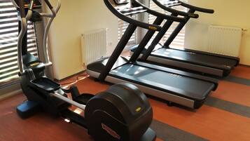 Un gimnasio con dos cintas de correr, una elíptica y una bicicleta estática.