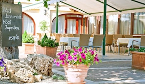 An outdoor cafe with tables and chairs, a chalkboard menu, and potted plants. - Betekints Wellness és Konferencia Hotel (Veszprem)