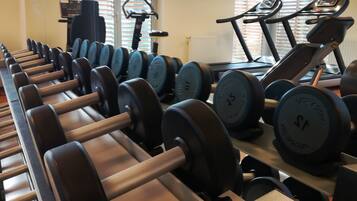 A gym with rows of dumbbells, treadmills, and a stationary bike.