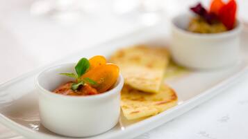 A white plate with two small bowls of food and a piece of flatbread.