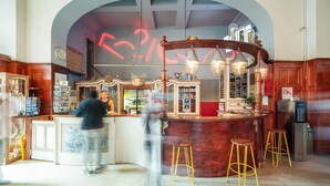Un espace bar doté d’un comptoir en marbre, de tabourets en bois et d’une enseigne au néon.