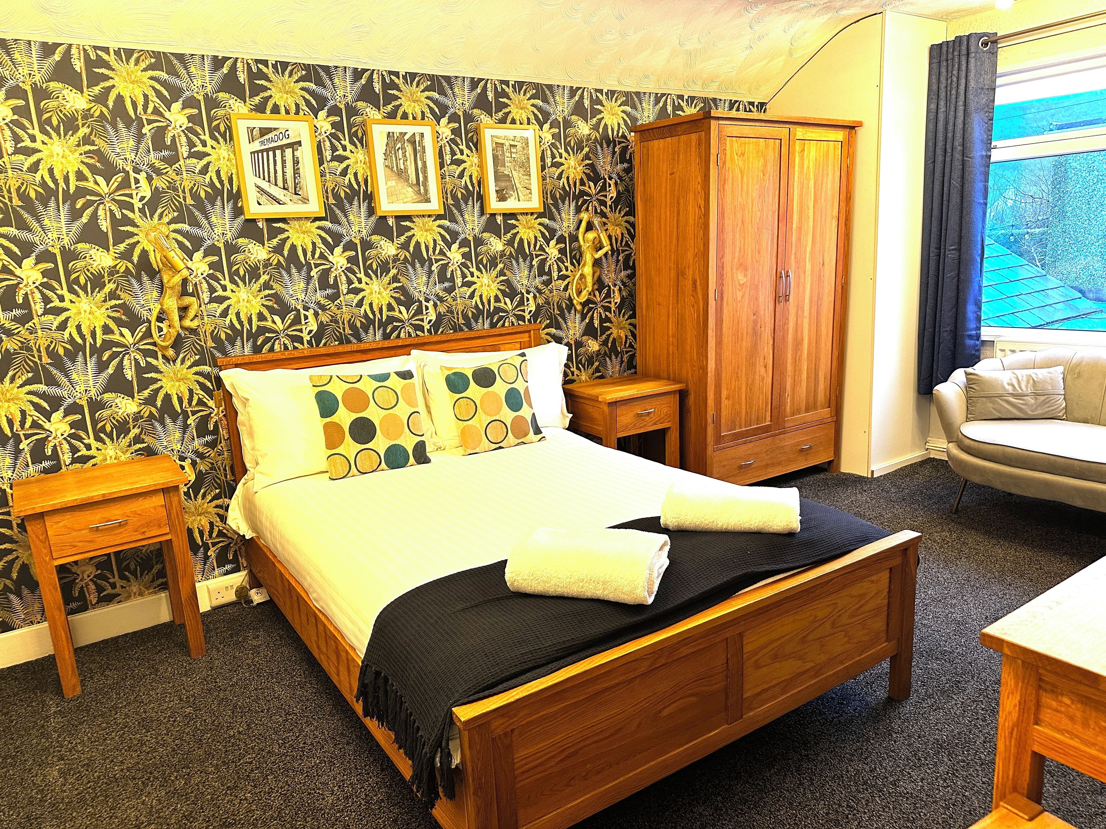 A bedroom with a bed, wooden wardrobe, and a window with curtains.