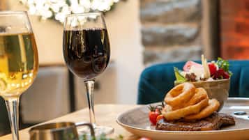 Une table à manger avec une assiette de nourriture, un verre de vin blanc et un verre de vin rouge.