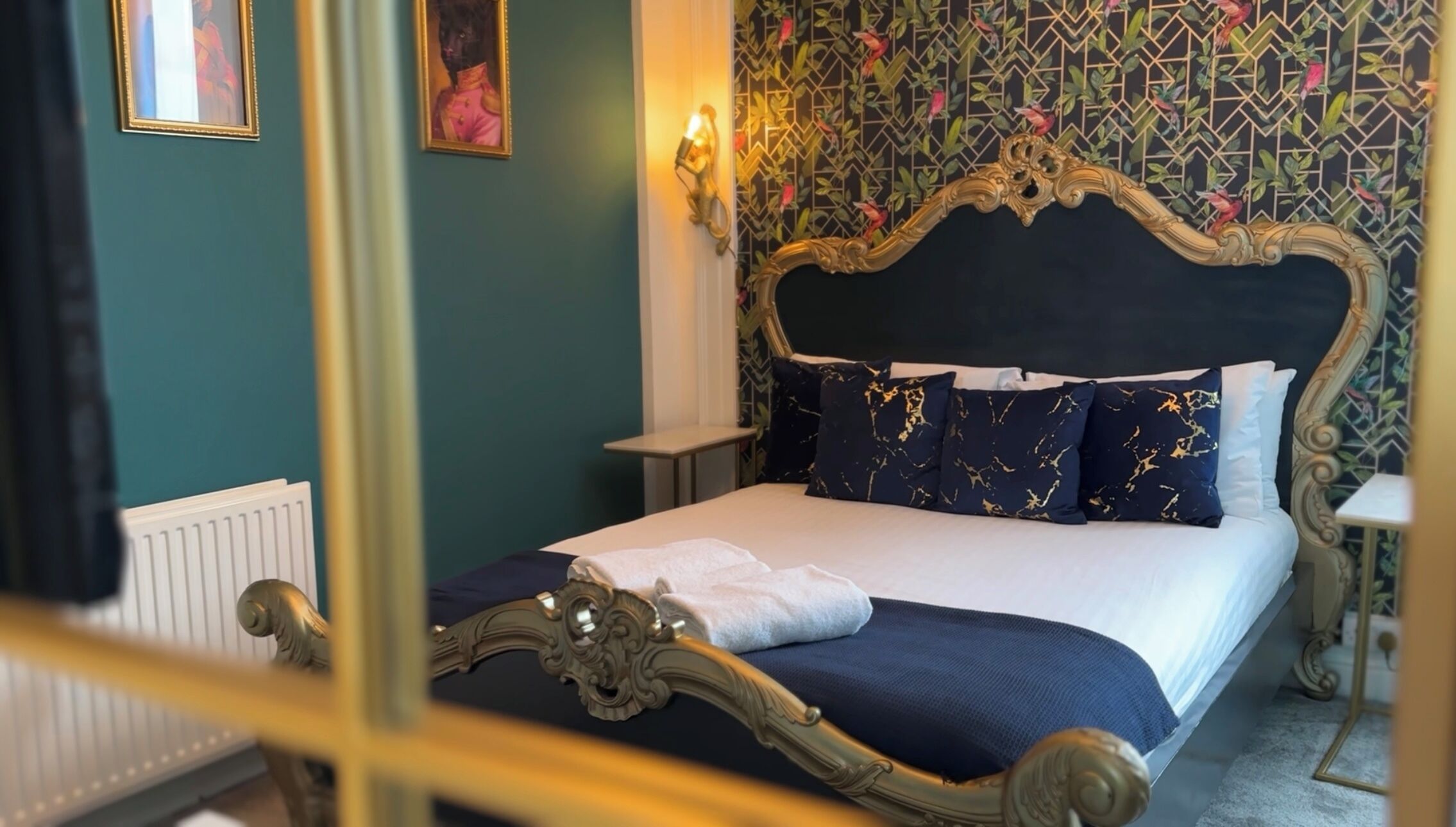 A bedroom with a bed, a nightstand, a wall-mounted light, and a radiator.