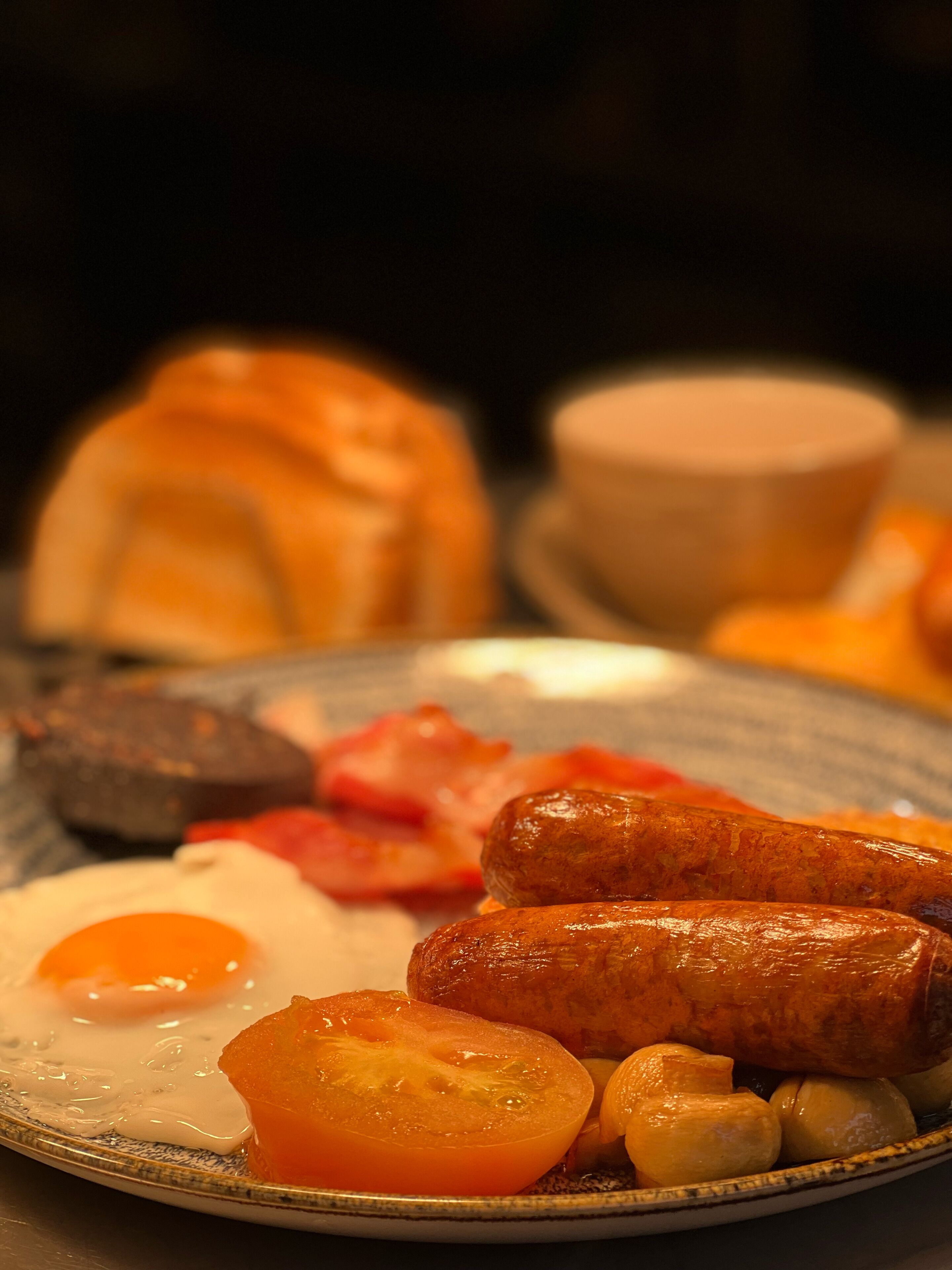 A plate of breakfast food including sausages, eggs, tomatoes, and mushrooms.