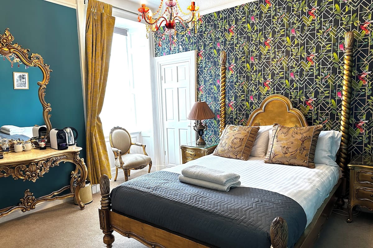 Un dormitorio con cama, tocador, silla, espejo y candelabro.