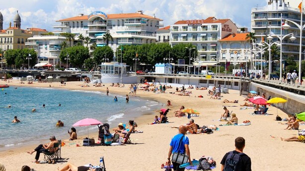 Um hotel à beira-mar com várias varandas, piscina e área de praia com guarda-sóis.