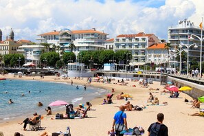 Un hotel a la vora de la platja amb múltiples balcons, una piscina i una zona d'ulls amb paraigües.