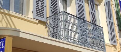 A hotel facade with multiple balconies, a sign indicating it is a hotel, and a door with a number.