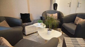 Uma sala de estar moderna com sofás cinza, uma mesa de centro branca e uma planta em vaso.