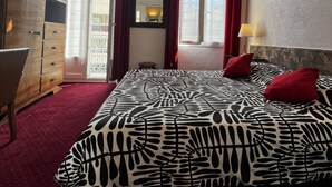 Quarto com cama, cômoda, espelho e janela com cortinas.