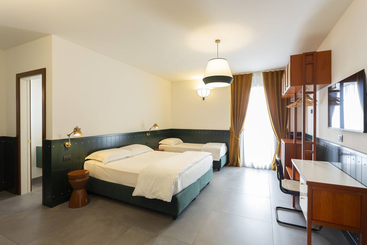 Una habitación de hotel con dos camas, un escritorio, una silla, un televisor y un armario.