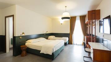 Une chambre d’hôtel avec deux lits, un bureau, une chaise, une télévision et une armoire.