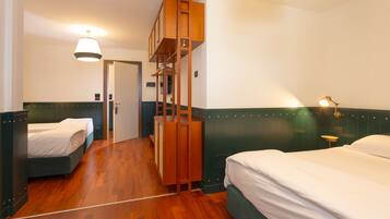 A hotel room with two beds, wooden furniture, and a unique loft-style bed.
