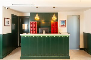 A reception area with a green counter, two pendant lights, and red storage units.