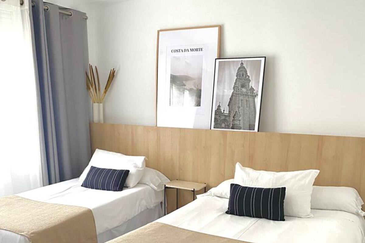 Habitación de hotel con dos camas, cabecera de madera y un cuadro enmarcado de Costa da Amore.