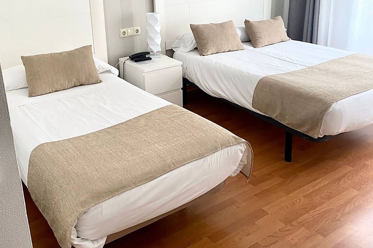 Habitación de hotel con dos camas, suelo de madera y pared a rayas.