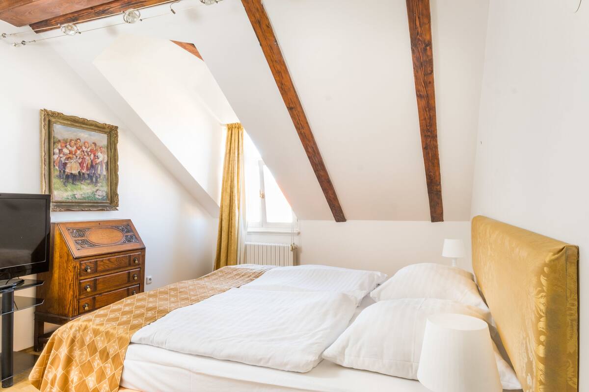 A bedroom with a bed, a dresser, a television, and a painting on the wall.