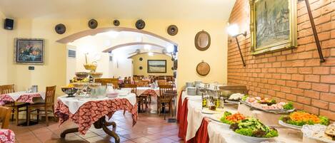 A dining area with multiple tables, a buffet with various food items, and a brick wall with a framed picture.